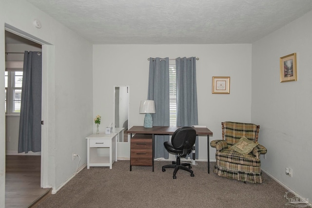 carpeted office space featuring a textured ceiling