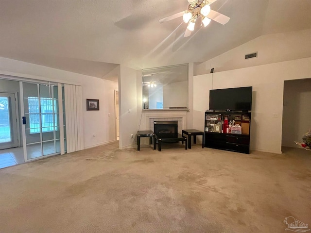 living room with a tiled fireplace, lofted ceiling, ceiling fan, and carpet