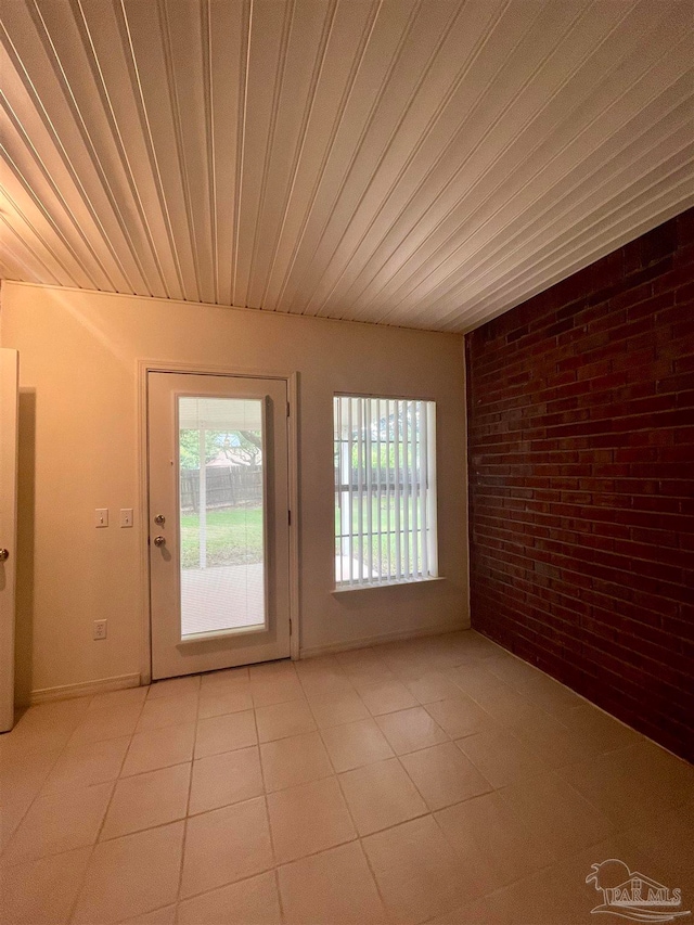 interior space featuring brick wall, wooden ceiling, and light tile patterned flooring