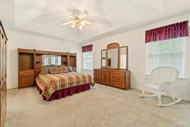 bedroom with baseboards, a raised ceiling, light carpet, and ceiling fan