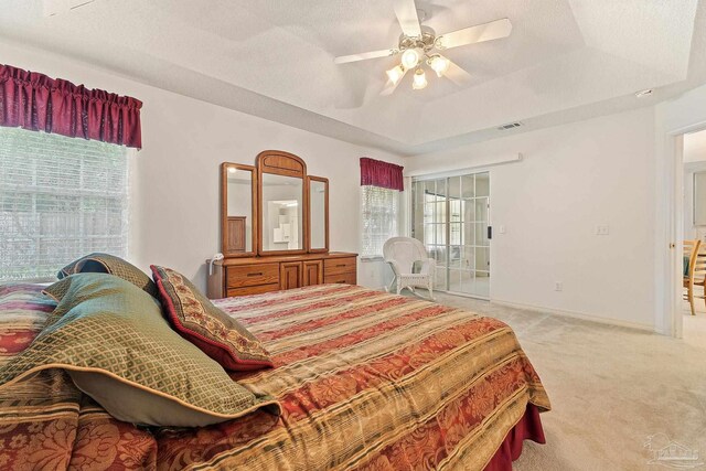 bedroom featuring visible vents, a tray ceiling, a textured ceiling, baseboards, and light colored carpet