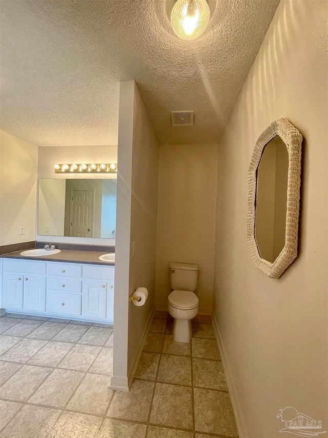 bathroom featuring tile patterned floors, toilet, a textured ceiling, and vanity