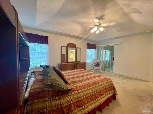 carpeted bedroom featuring multiple windows, ceiling fan, a raised ceiling, and a textured ceiling