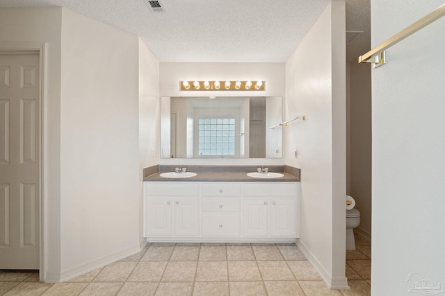 bathroom featuring a textured ceiling, toilet, visible vents, and a sink