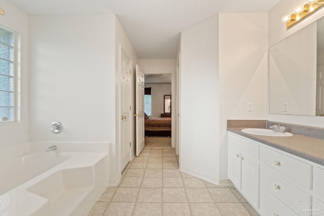 full bathroom featuring tile patterned flooring, vanity, a garden tub, a textured ceiling, and ensuite bath