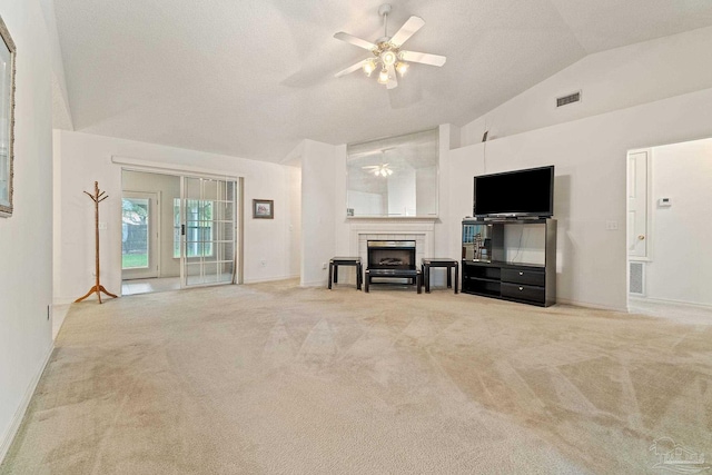 unfurnished living room with visible vents, lofted ceiling, carpet flooring, a fireplace, and a ceiling fan