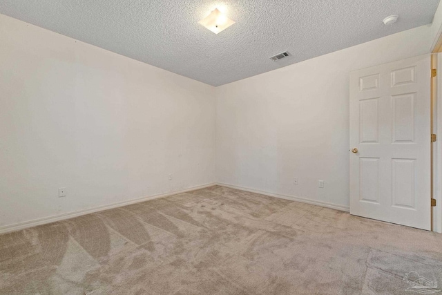 carpeted spare room with visible vents, baseboards, and a textured ceiling