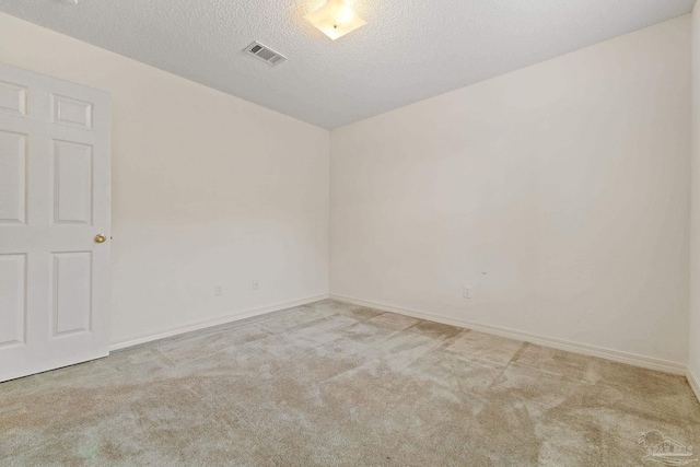 spare room featuring baseboards, carpet, visible vents, and a textured ceiling