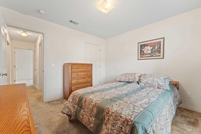 bedroom featuring visible vents, carpet, and a textured ceiling