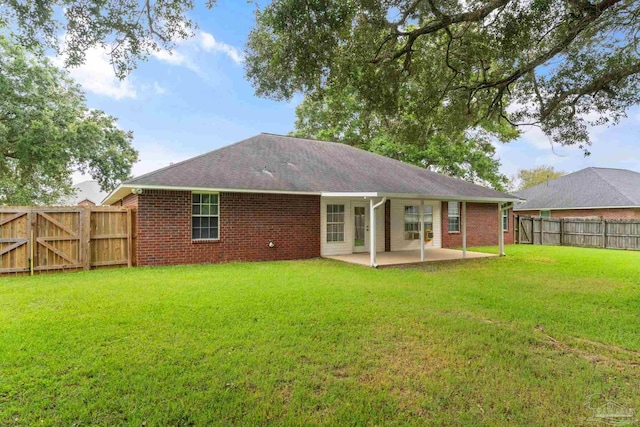 back of house featuring a patio, a yard, a fenced backyard, and brick siding