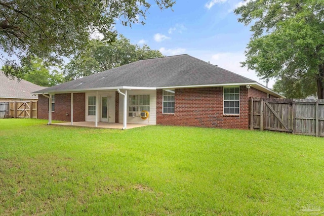 back of property featuring a patio, a gate, a yard, and brick siding