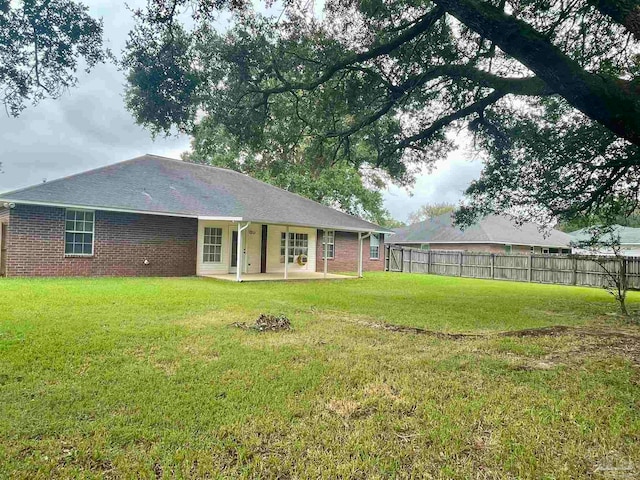 rear view of house with a lawn and a patio