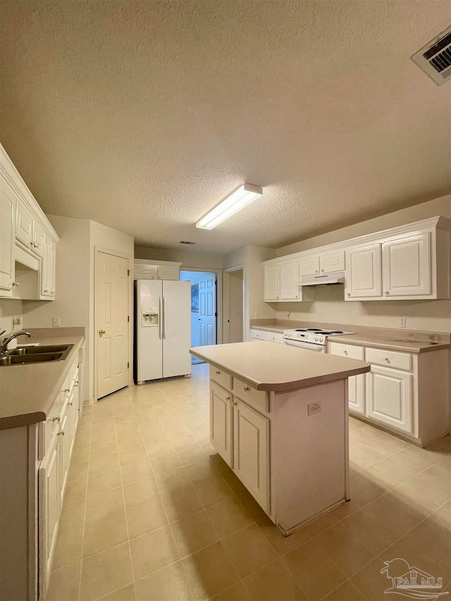 kitchen featuring white appliances, white cabinetry, sink, a kitchen island, and a textured ceiling