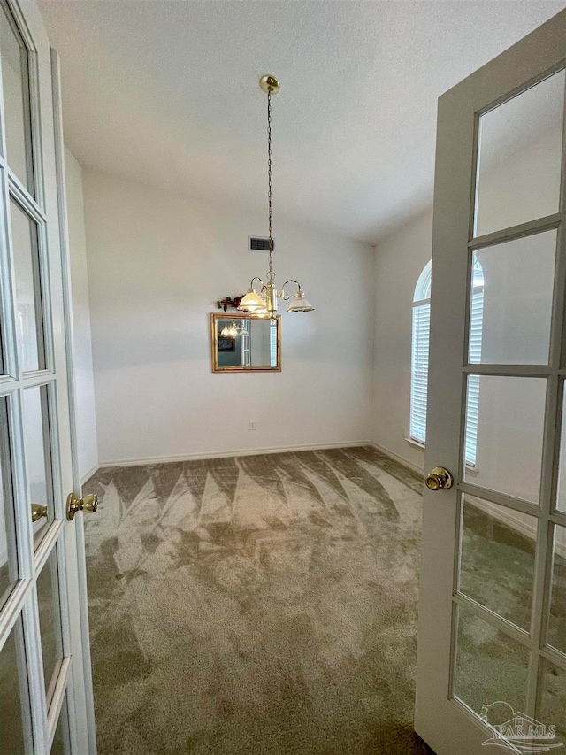 spare room with vaulted ceiling, a chandelier, and carpet floors