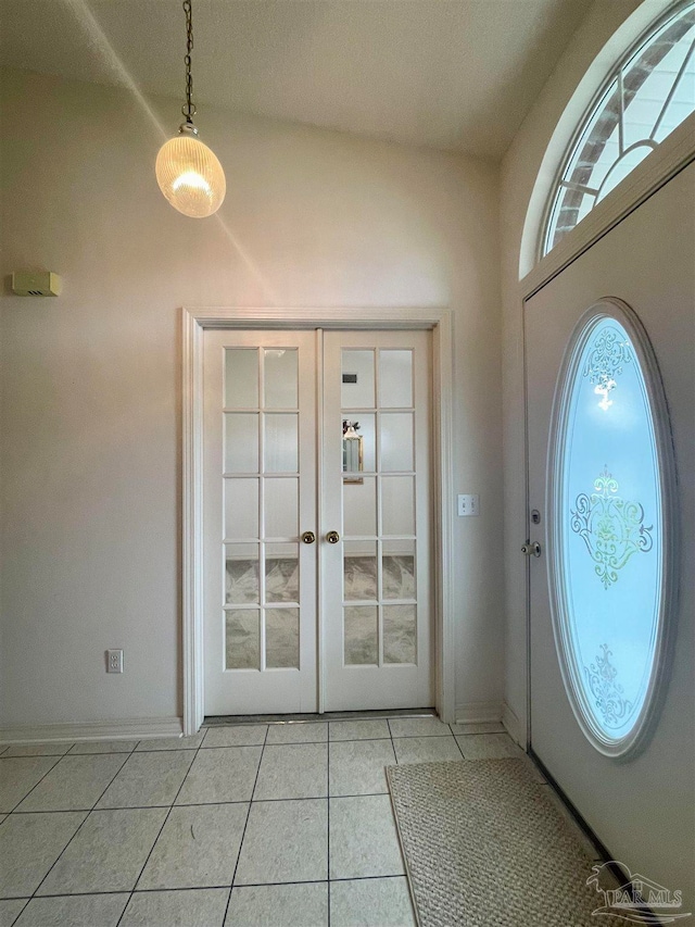 entryway with vaulted ceiling, french doors, and light tile patterned flooring