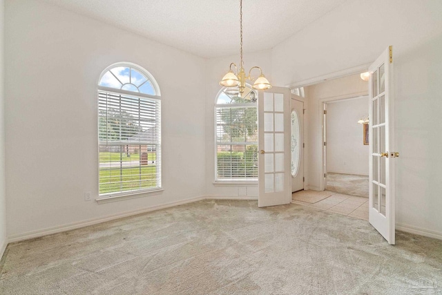 empty room featuring carpet flooring, french doors, baseboards, and an inviting chandelier