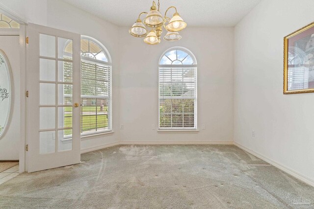 unfurnished dining area with french doors, carpet floors, baseboards, and a chandelier