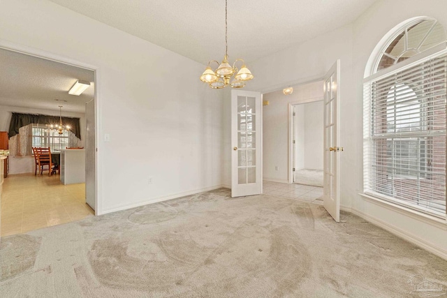 carpeted spare room featuring tile patterned floors, french doors, baseboards, and a notable chandelier