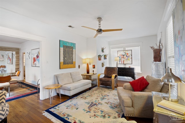 living room featuring a ceiling fan, visible vents, and wood-type flooring