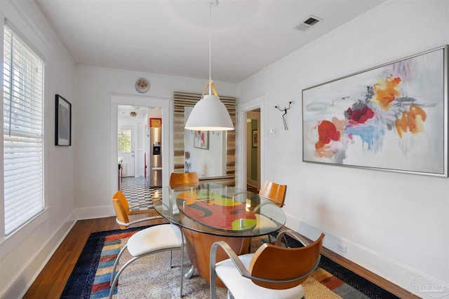 dining space with visible vents, wood finished floors, and baseboards