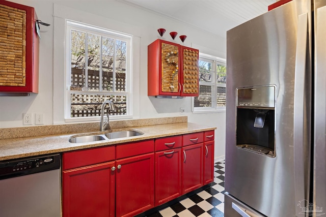 kitchen featuring a sink, red cabinets, appliances with stainless steel finishes, dark floors, and light countertops