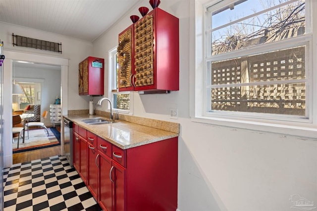 kitchen featuring tile patterned floors, ornamental molding, a sink, red cabinets, and dishwasher