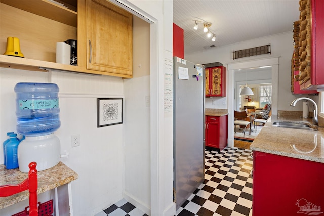 kitchen featuring tile patterned floors, a sink, freestanding refrigerator, rail lighting, and light countertops