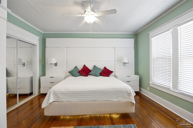 bedroom with wood finished floors, a closet, crown molding, baseboards, and ceiling fan