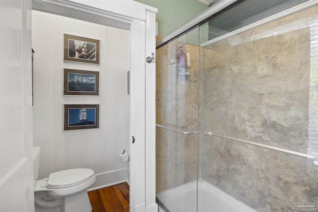 full bath featuring baseboards, toilet, wood finished floors, and a shower stall