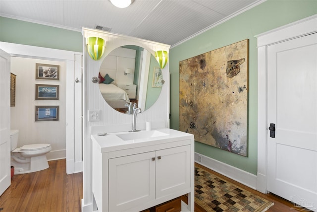 bathroom featuring crown molding, toilet, and wood finished floors