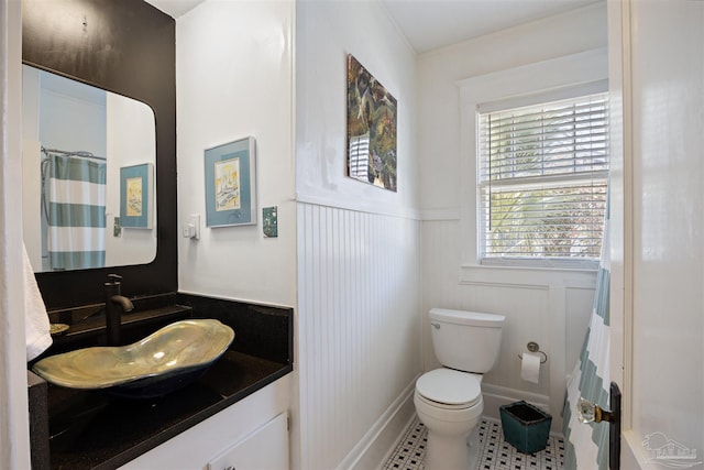 full bathroom featuring tile patterned flooring, wainscoting, toilet, and vanity