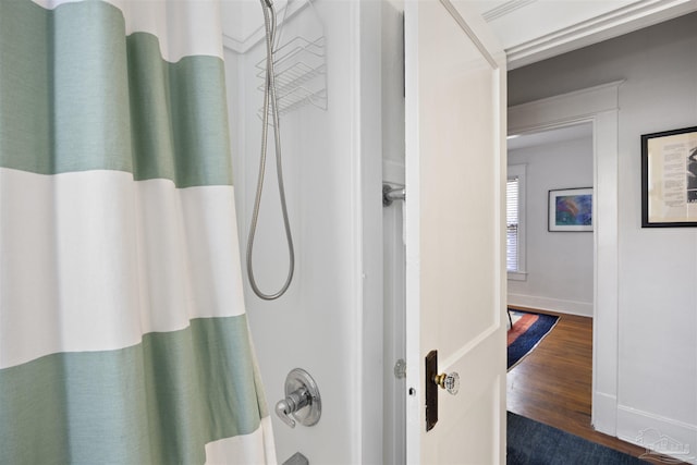 bathroom featuring shower / bath combination with curtain, baseboards, and wood finished floors