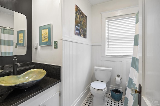 bathroom with a wainscoted wall, toilet, curtained shower, tile patterned flooring, and vanity