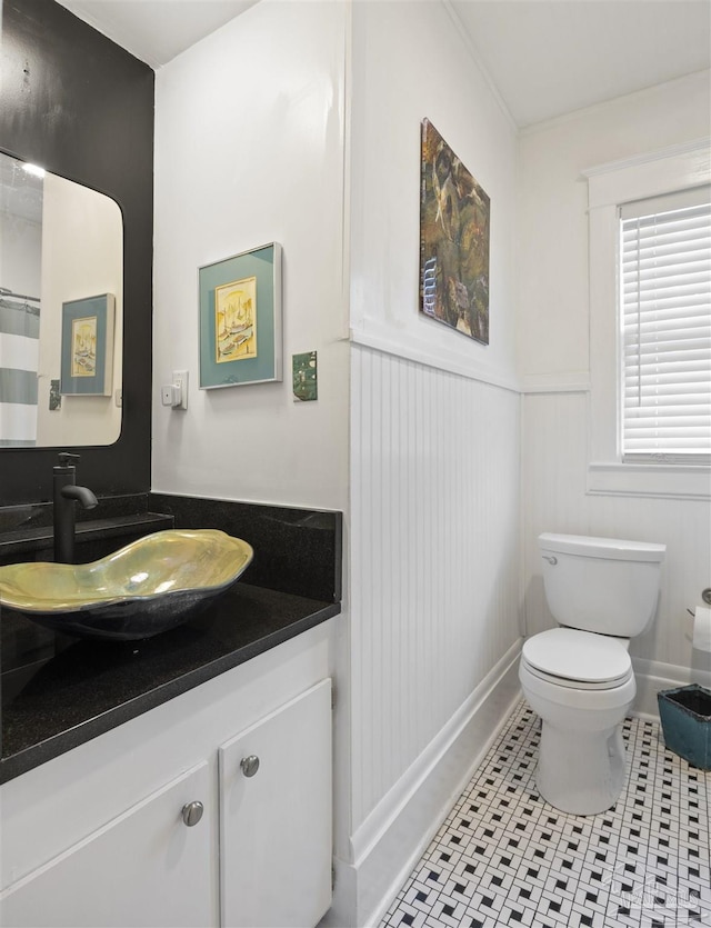 full bath featuring vanity, tile patterned floors, toilet, and wainscoting