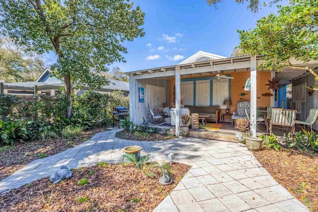 rear view of property with an outdoor living space, a ceiling fan, and a patio area