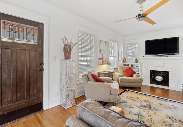 living room with a fireplace, a healthy amount of sunlight, hardwood / wood-style floors, and a ceiling fan