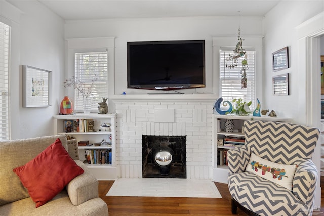 living room with wood finished floors, a fireplace, and crown molding