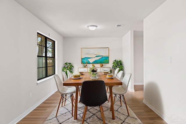 dining space with baseboards, visible vents, and wood finished floors
