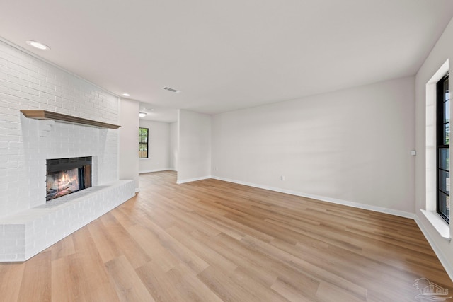 unfurnished living room with a fireplace, visible vents, baseboards, and light wood-style floors
