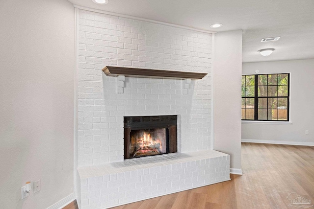 details with a fireplace, visible vents, wood finished floors, and baseboards