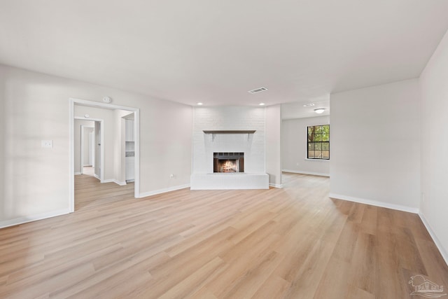 unfurnished living room featuring light wood finished floors, recessed lighting, a brick fireplace, visible vents, and baseboards