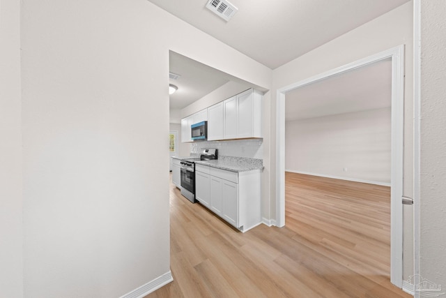 kitchen with white cabinetry, visible vents, stainless steel electric range oven, and light wood finished floors