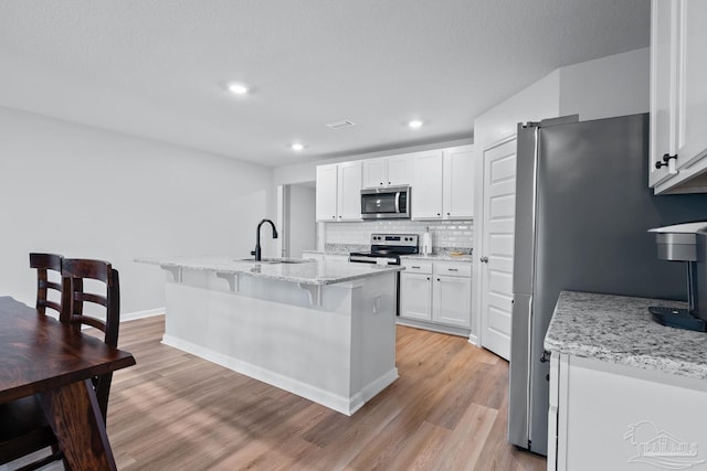 10985 Blacktail Loop, Pensacola, FL 32526 - kitchen with stainless steel appliances, a sink, light wood finished floors, white cabinetry, and recessed lighting