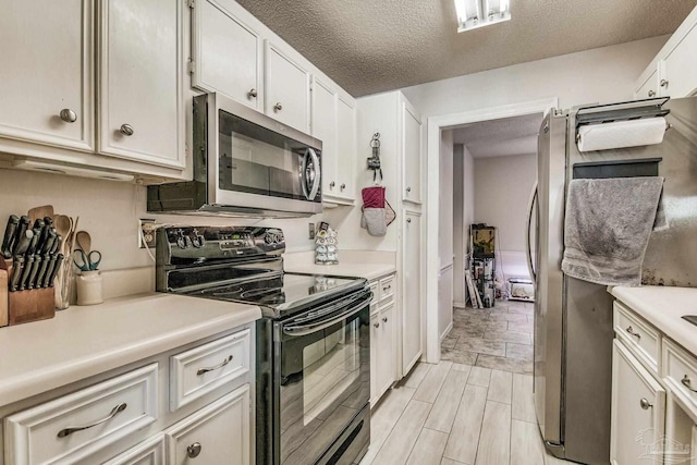 kitchen with a textured ceiling, white cabinets, and stainless steel appliances