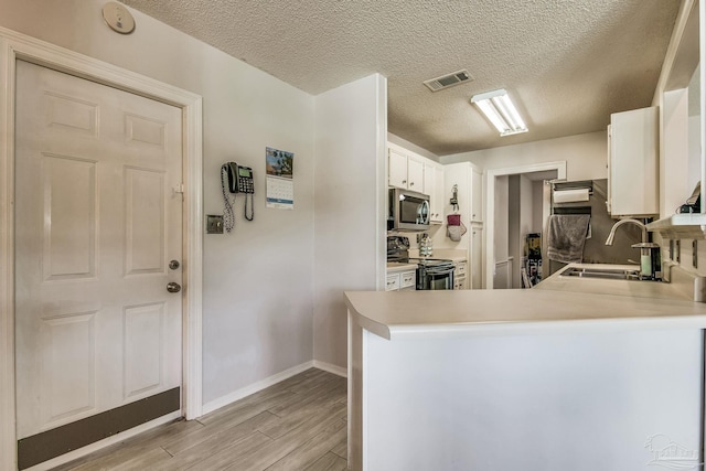 kitchen featuring sink, kitchen peninsula, white cabinetry, light hardwood / wood-style floors, and stainless steel appliances