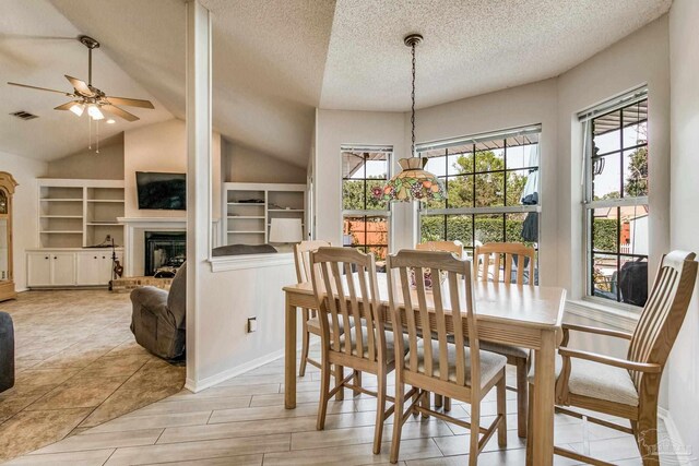 dining room featuring a textured ceiling, ceiling fan, light wood-type flooring, and vaulted ceiling