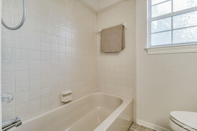 bathroom with toilet and tiled shower / bath