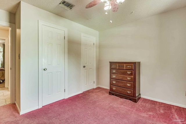 unfurnished bedroom featuring carpet, a textured ceiling, and ceiling fan