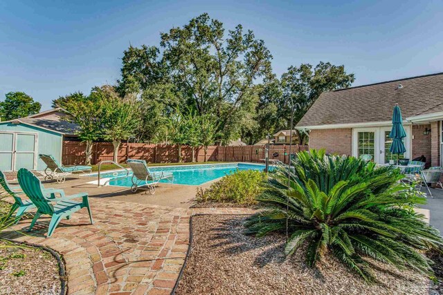 view of swimming pool featuring a patio and a shed