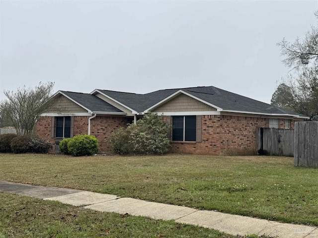 view of side of home featuring fence, a lawn, and brick siding